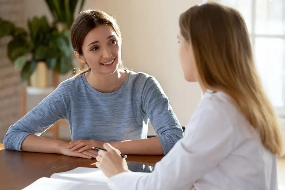 A smiling student talking with a counselor who is taking notes across a table